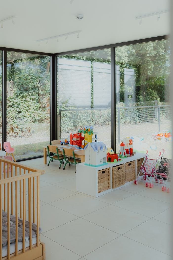 Speelhoek met wieg, tafeltje en poppenwagens, met zicht op de tuin